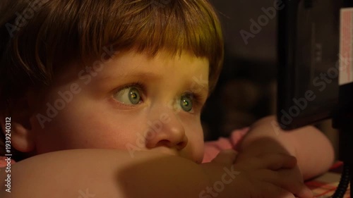 Close up of child eyes illuminated by smartphone screen in dark room. Concept of screen time, children and digital technology use.