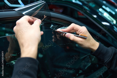 Car detailer cutting away PPF from automobile window surface