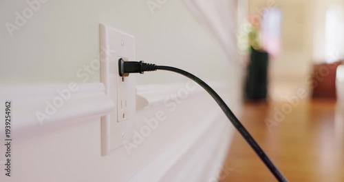 Hand plugging and unplugging electric plug into wall outlet
