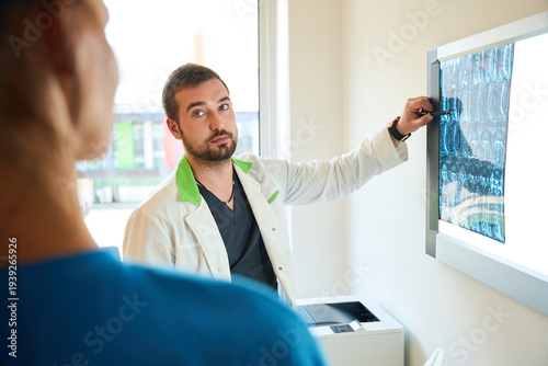 Caucasian doctor discussing medical scan with colleague in office