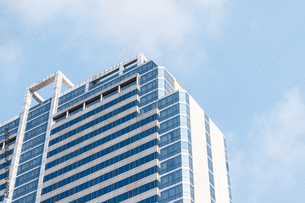 Fototapeta premium Bottom up view blue office building with blue sky background