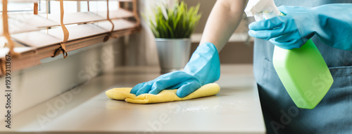 Foto Housekeeper doing chores concept, Close-Up view of housemaid cleaning furniture surface with sanitizer spray and wiping with wet cloth in living room