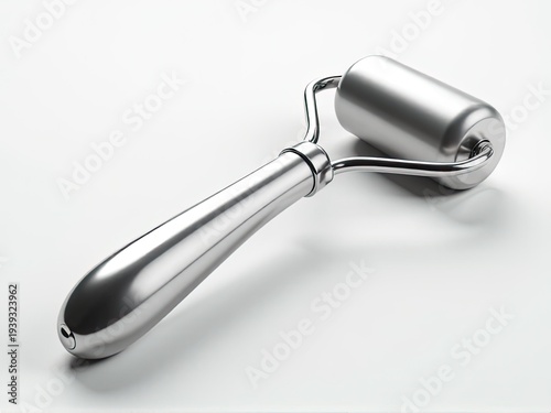 A metal roller with a handle on a white surface, ideal for use in photography studios or workshops