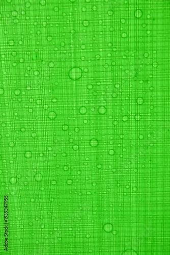 Vibrant green fabric with water droplets on textured surface
