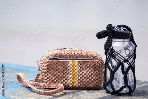 Crochet bag and water bottle on rustic surface outdoors