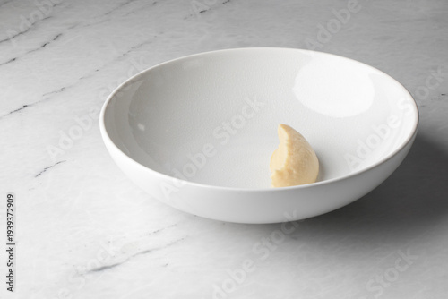 Fényképezés A solitary crescent dumpling rests in an expansive porcelain dish, invoking mini