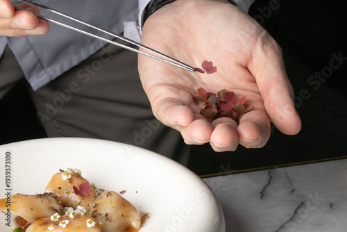 Konstfotografi Chef's hand garnishing delicate blossoms, culinary artistry blooms, nod to Cherr