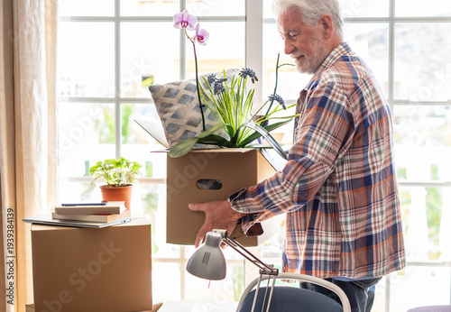 Active senior man involved in moving house moving cardboard boxes, concept of relocation, retirement, new life, buying, renting, apartment, house