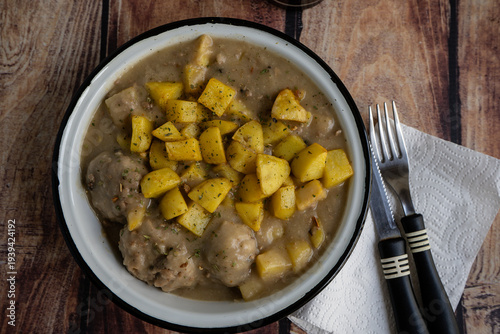 Meatballs and potatoes in sauce on wooden table