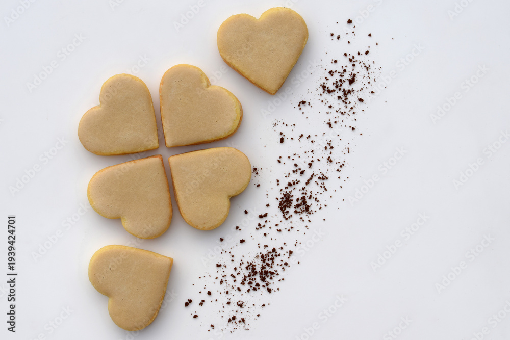 Obraz premium Heart-shaped cookies with coffee filling and icing, with instant coffee on white background, copy space for text