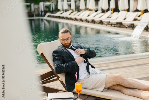 Foto Businessman relaxing by the pool after work, loosening his tie