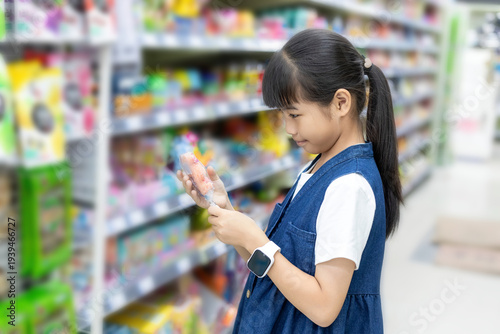 A young Chinese girl wearing a children's smartwatch buys snacks at a supermarket
