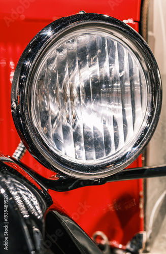 Close up view of headlight on vintage car showing shine and details at classic car show in bright indoor setting