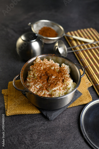 Traditional Rice Pudding with Cinnamon in Dark Metal Casserole on Burlap with Metal Jug and Bamboo Mat — Rustic Dark Food Styling