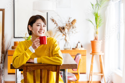 Schilderij op canvas 椅子に反対向きに跨いで座りコーヒーを飲む女性