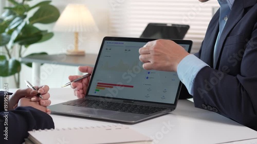 Business executives analyzing financial charts on a laptop during an office meeting