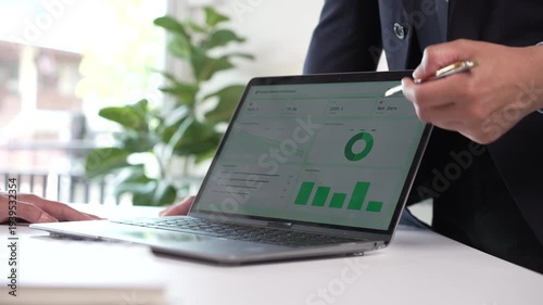 Business professional pointing at a carbon neutral dashboard on a laptop screen