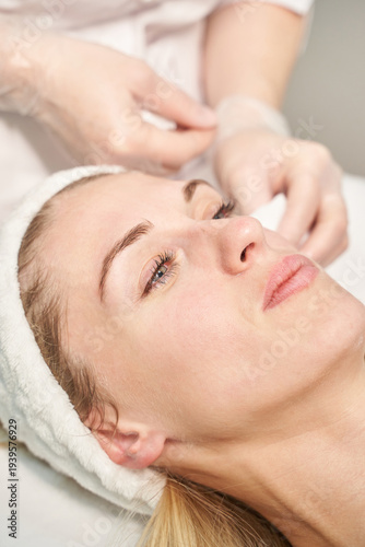 Caucasian female adult receiving facial treatment in spa setting with relaxed expression and headband.