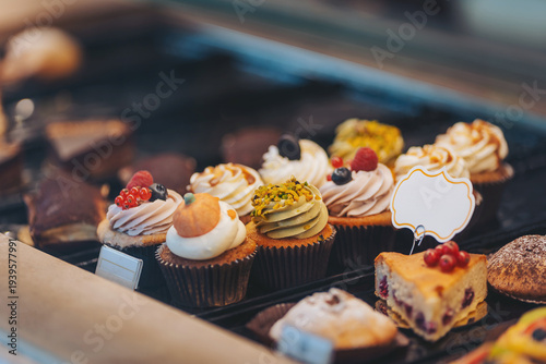 A vibrant selection of cupcakes showcases various toppings and flavors in a charming bakery. Sweet treats tempt passersby with their delightful appearances