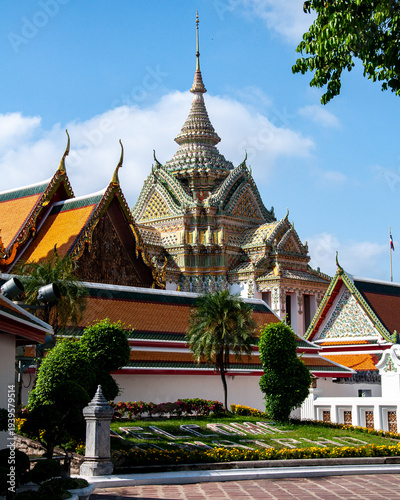 A portrait shot of the elaborate scripture hall at Wat Pho in Bangkok under a blue sky