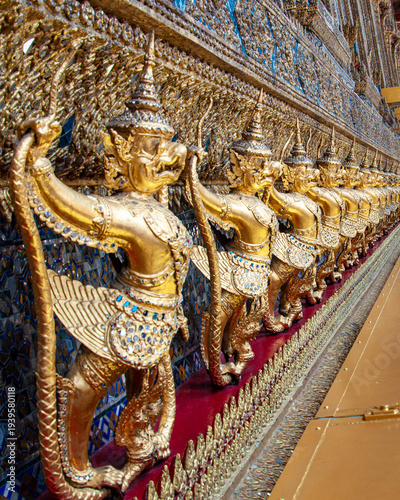 Intricate gold statues line a wall at Wat Phra Kaeo in Bangkok