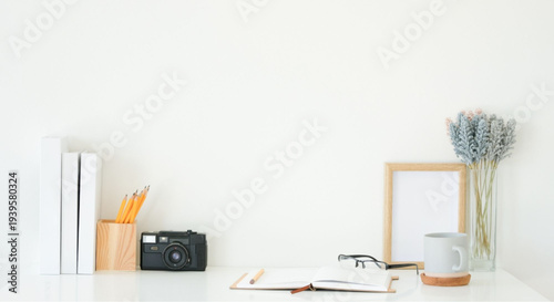Cozy workspace with camera, books, and flowers on white desk
