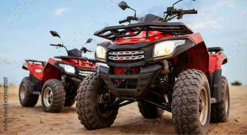 Red ATVs parked on sandy terrain with blue sky background