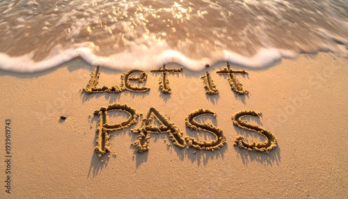 Inspirational phrase let it pass written in beach sand with gentle ocean waves approaching for mindfulness and emotional release conceptual photography imagery