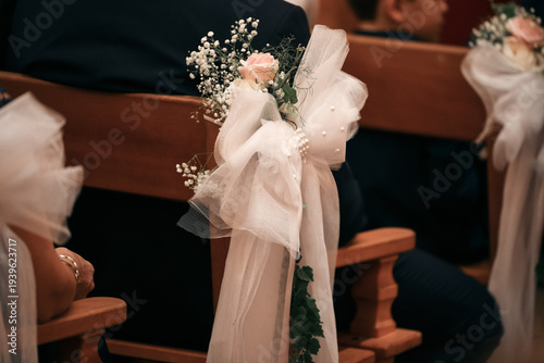 Closeup of tulle bow with roses on wedding church wooden pew
