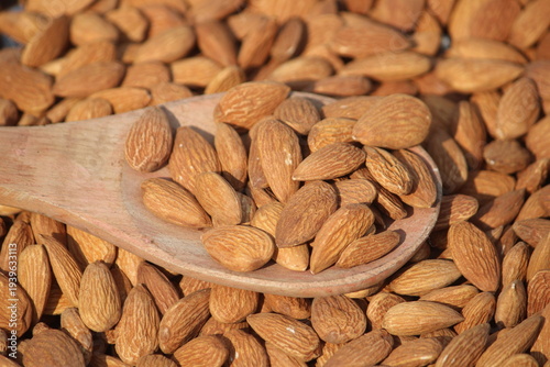 Dried almonds. Almond kernels lie in wooden spoon. Top view of nuts close-up. Advertising photography for marketplaces or online stores.