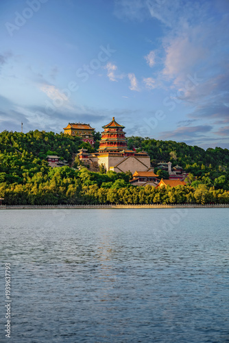 Tower of Buddhist Incense rising above Kunming Lake at the Summer Palace in Beijing, China, surrounded by green hills under blue sky in early autumn.