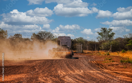 Heavy transport truck driving on dirt road kick up dust cloud rural construction site infrastructure