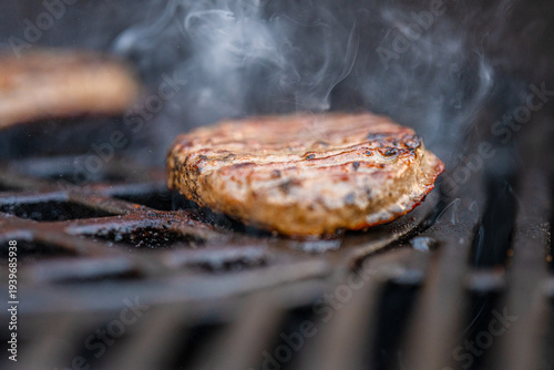 Canvas Print juicy grilled burger patty sizzling on barbecue grill.