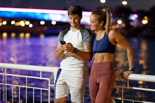 Fitness couple taking a break using smartphone
