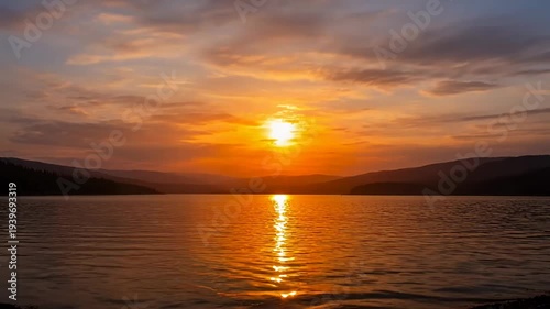 A breathtaking sunset over a serene lake with distant mountains
