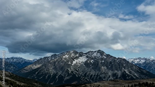 Spectacular mountain range with snowcapped peaks under a cloudy, dynamic sky