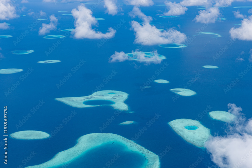 Obraz premium Maldives aerial drone view of turquoise ocean with coral reef atolls and sparkling sunlight, pristine exotic tropical paradise beach scenery perfect for travel vacation