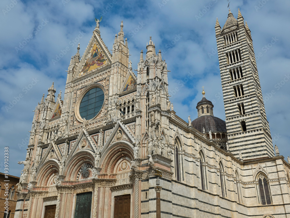 Fototapeta premium The Gothic-Romanesque facade of Siena Cathedral (Duomo di Siena) featuring the iconic striped bell tower and ornate marble sculptures, Tuscany, Italy