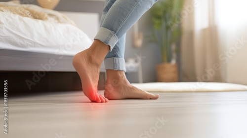 A person experiences sharp pain in their foot, specifically the ball of their sole, highlighted with a red glow on a light wooden floor in a bedroom setting.