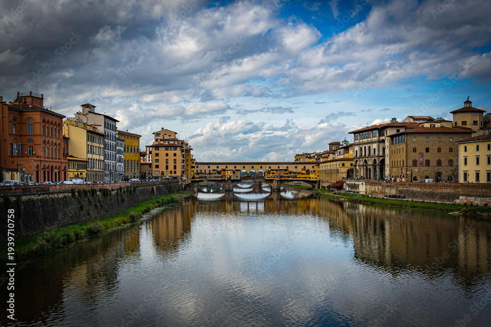 Fototapeta premium View of Ponte Vecchio over the Arno River in Florence during late afternoon with clouds in the sky