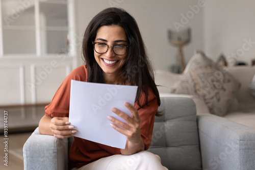 Photos Beautiful Brazilian woman sit in armchair at home, smiling while reading letter