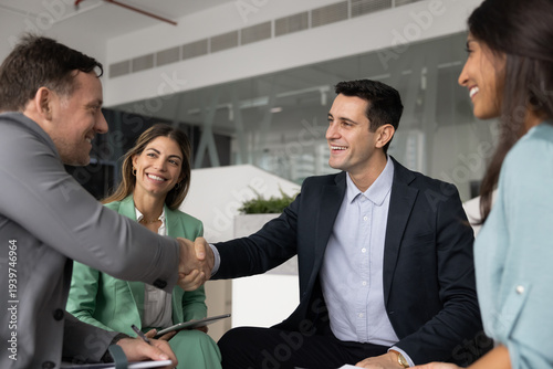 Two diverse male colleagues celebrating teamwork success with handshake on informal staff meeting in office showing mutual respect trusted partnership making agreement after professional networking