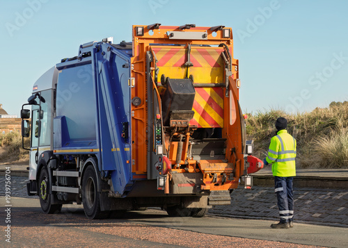 Fotografie Sanitation worker operating refuse collection truck during waste pickup
