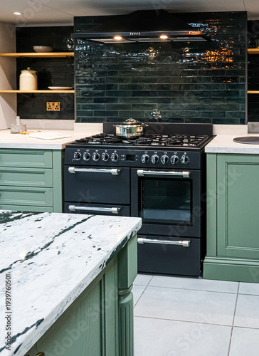 Contemporary kitchen interior featuring dark green metro tiles, a black range cooker, and a white marble island countertop