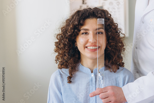 Tablou pe pânză Female patient undergoing an optometry vision check, prism bar testing her eye a