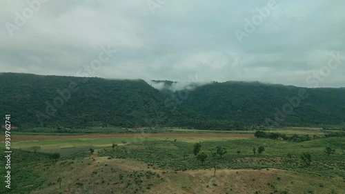 Cinematic drone aerial view of a winding road through lush tea gardens and forest hills in Jaflong, Sylhet, Bangladesh. Peaceful countryside landscape with clouds gathering