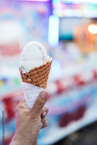 Hand holding an ice cream cone at a fair