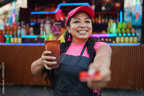 Latin entrepreneur woman offering payment and Michelada drink