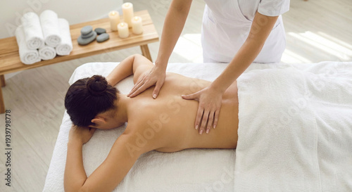 Professional spa therapist performing a relaxing back massage on a client lying on a massage table in a calm wellness environment. Warm lighting and natural tones create a soothing atmosphere represen