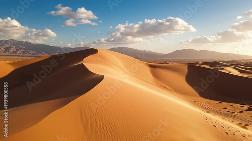 Desert sand dunes under a blue sky with clouds